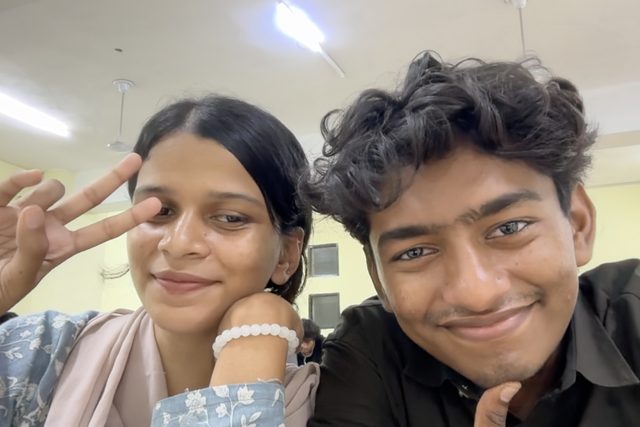 Two friends smiling, with a playful peace sign.