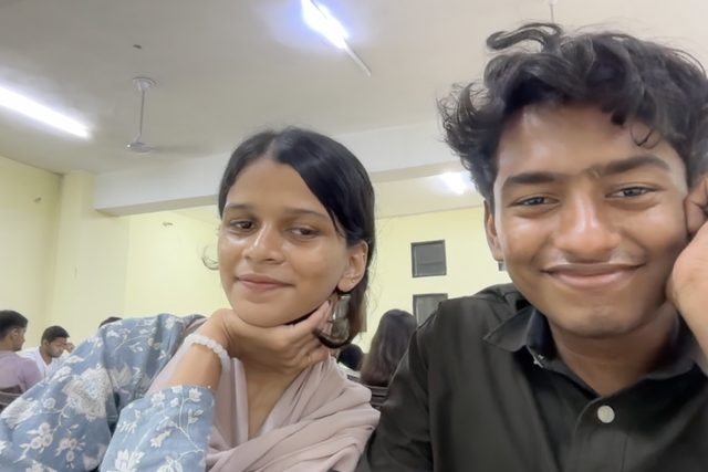 Two friends sitting together and smiling at the camera.