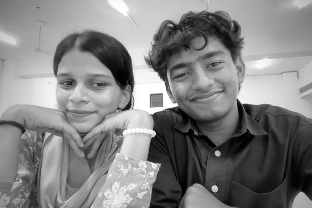 A black-and-white portrait of two friends smiling side by side.