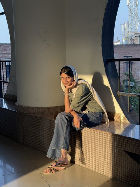 A portrait seated by a tall window in afternoon light.