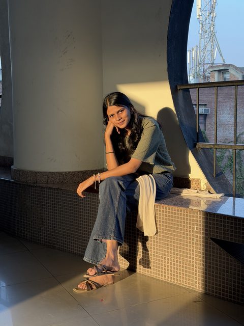 A sunlit portrait seated by a window, with a hand beneath the chin.