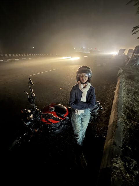 A portrait beside a motorcycle under night-time lights.