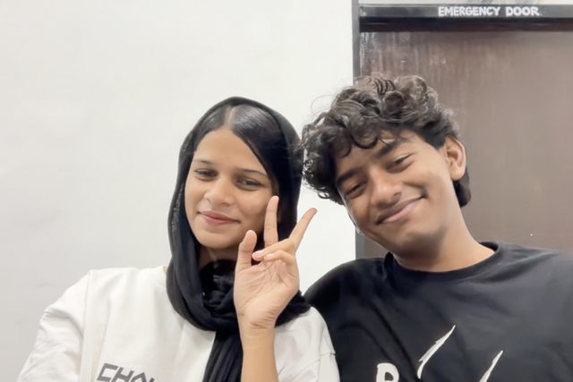Two friends making a peace sign and smiling.