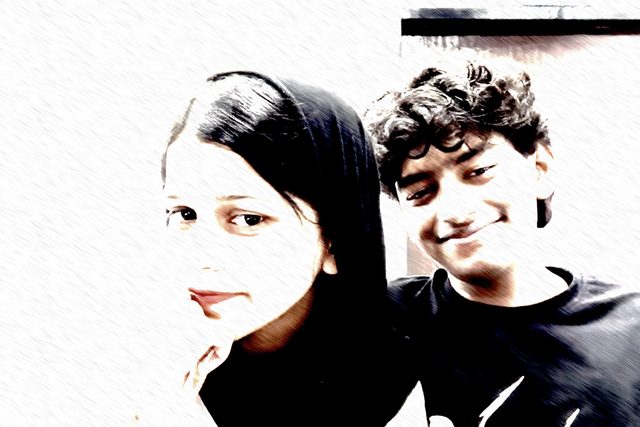 A high-contrast selfie with two friends leaning toward the camera.