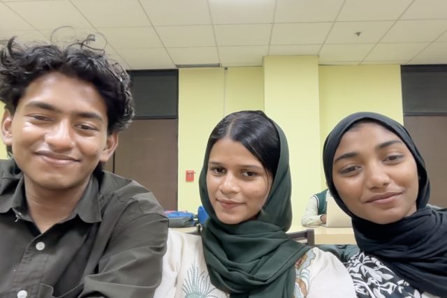 Three people looking at the camera in a shared selfie.