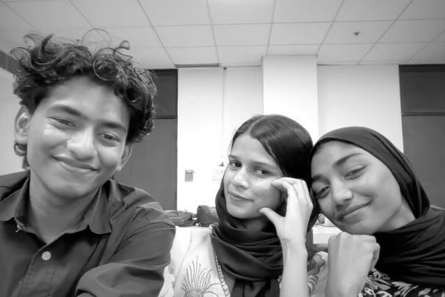 A black-and-white group selfie with playful hand gestures.