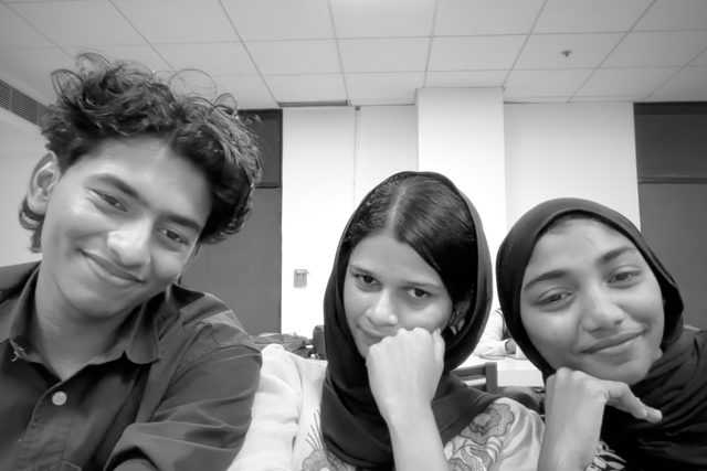 A black-and-white group portrait with three people facing the camera.