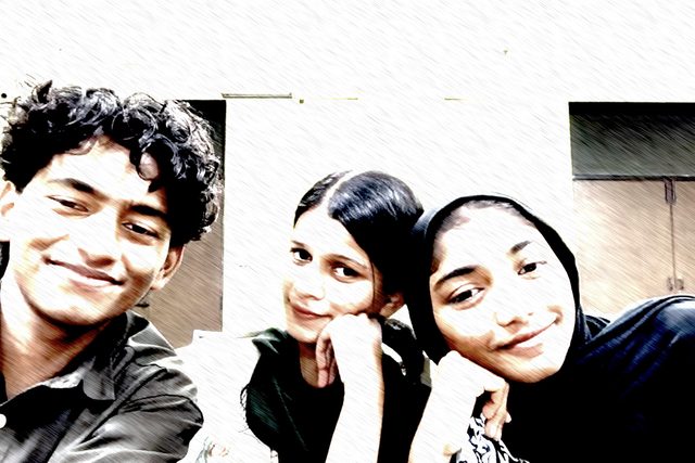 A high-contrast group selfie with three smiling people.